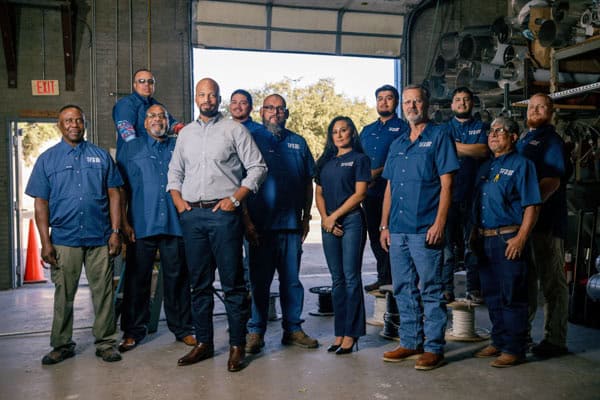 Tecton Facilities Solutions team shot. Woman and men dressed in Tecton branded shirts standing in construction area of a building.