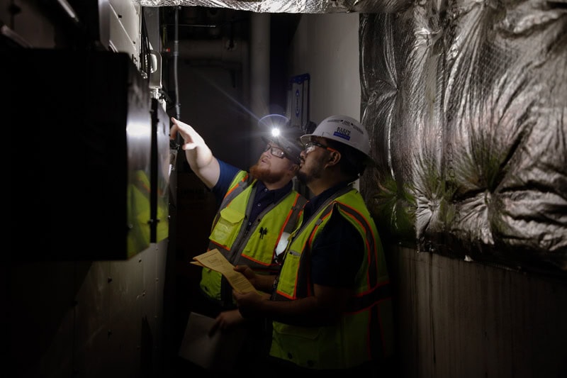 Tecton workers in safety gear working on electrical panel