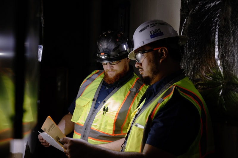 Tecton workers in safety gear working on electrical panel